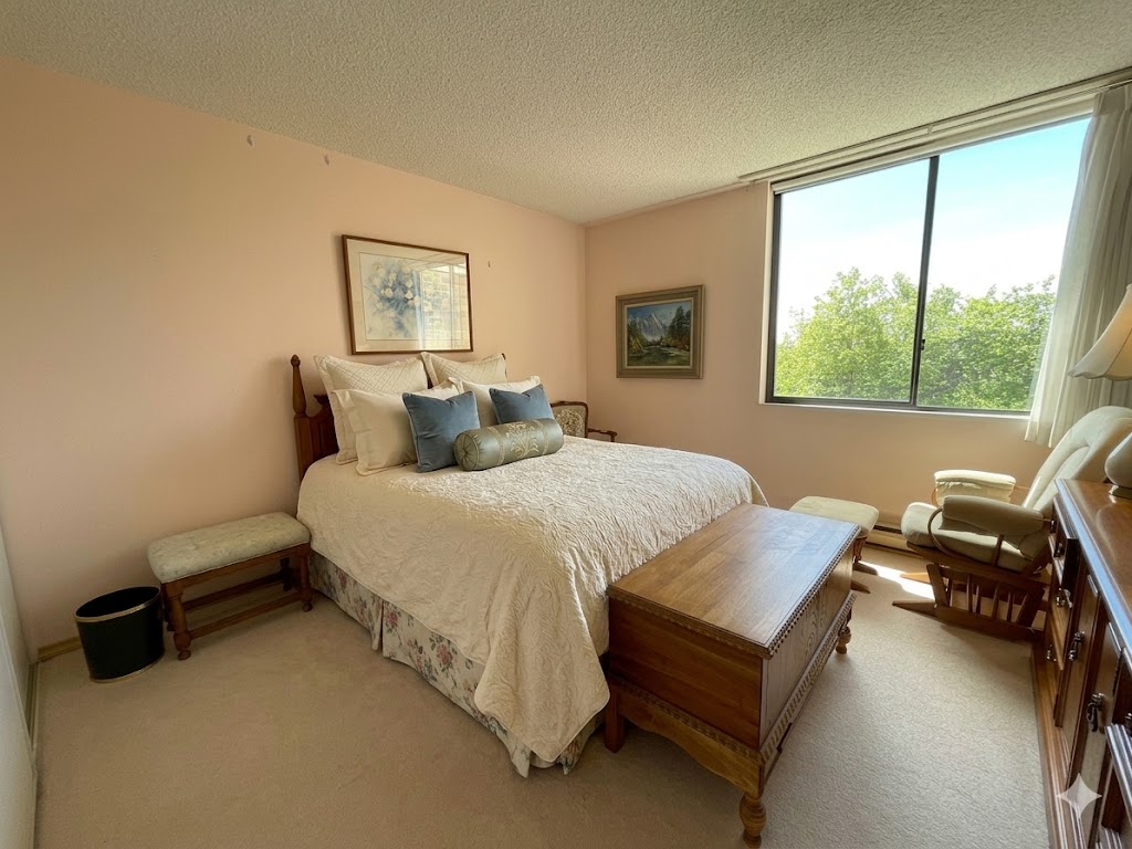 2225belleville2b | Apartments Homes Suites for Rent Victoria BC A cozy bedroom with a large window showing green trees a wooden bed and matching furniture including a chest at the foot of the bed and a chair by the window