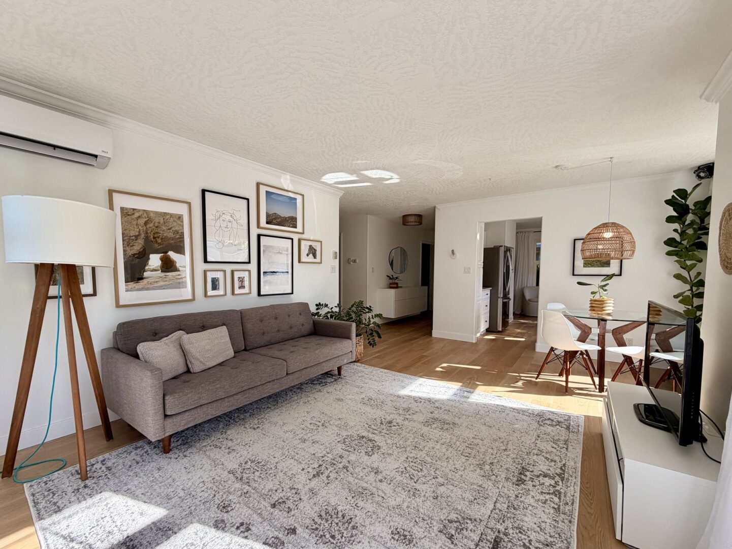 Cozy living room with a gray sofa gallery wall and a tripod floor lamp near a light rug and wooden floor