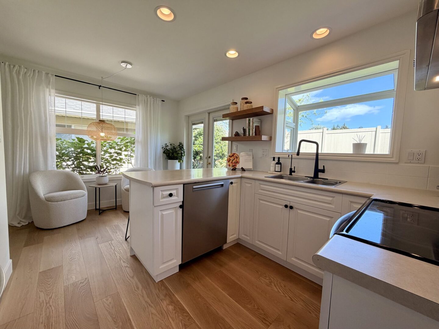 Bright modern kitchen with white cabinets and an island open shelving and a large window bringing in natural light