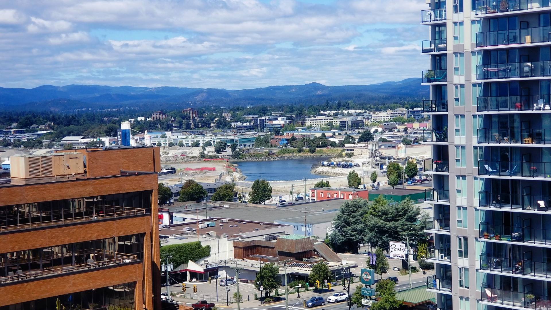 110629B | Apartments Homes Suites for Rent Victoria BC Cityscape with a river wdding between midrise buildings and distant hills a tall glass fronted apartment building dominates the right foreground