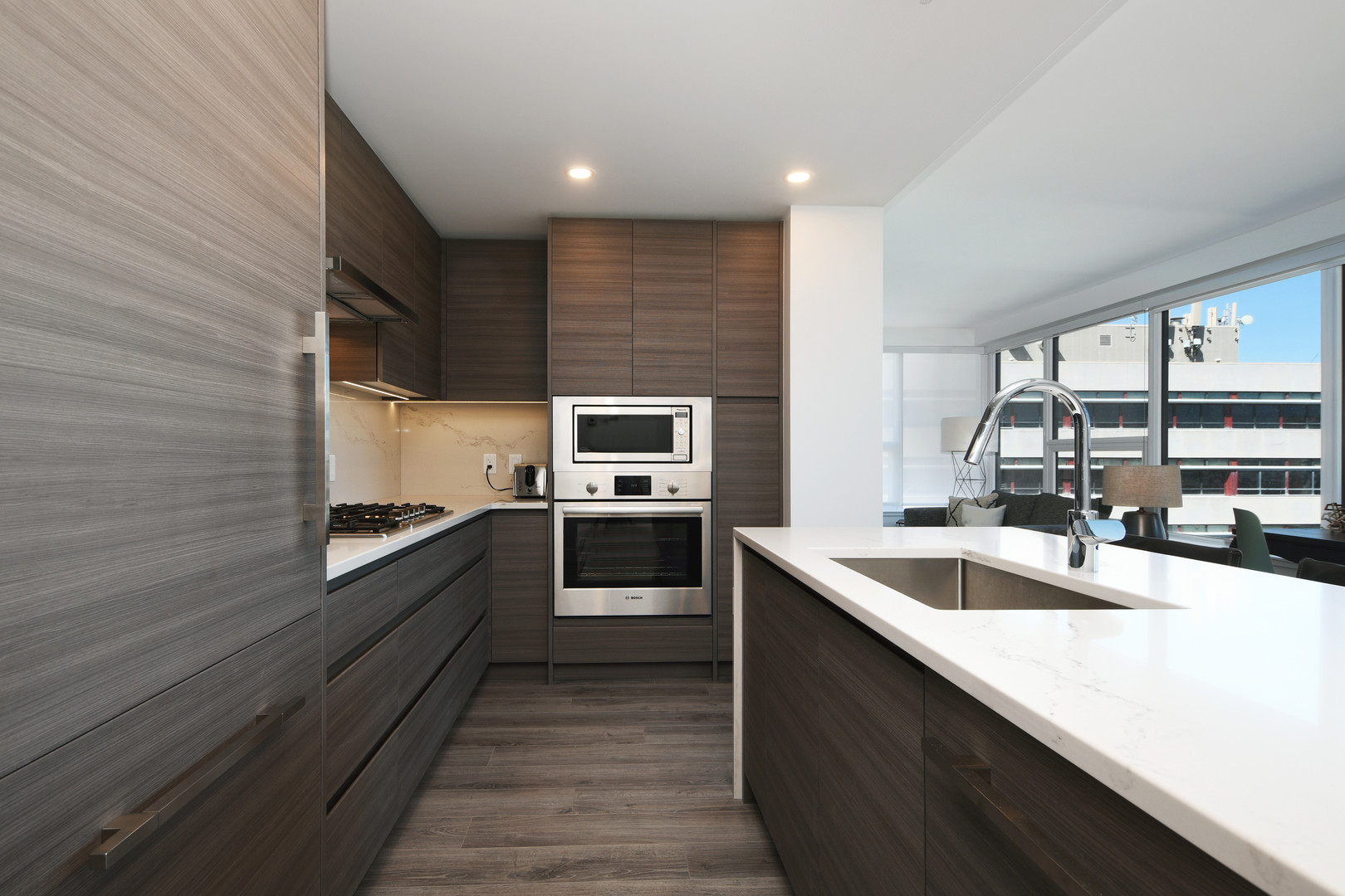 110643 | Apartments Homes Suites for Rent Victoria BC Modern kitchen with dark wood cabinets stainless steel ovenmicrowave and a white marble island An open concept kitchen featuring a gas cooktop tall pantry and a white quartz island