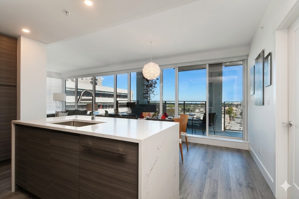 1106kitchen4 | Apartments Homes Suites for Rent Victoria BC Modern kitchen with a white marble island and dark wood cabinetry opening to a bright living area with large windows and a balcony view