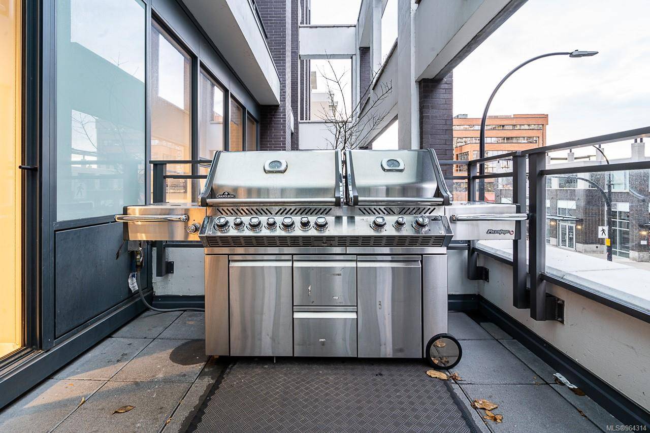 777bbq | Apartments Homes Suites for Rent Victoria BC Stainless steel outdoor barbecue grill on a balcony with glass doors and city buildings in the background