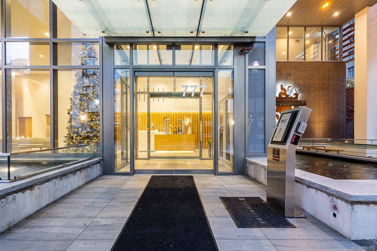 Glass front entrance to a modern building with a lobby and a lit Christmas tree visible inside number 777 above the door