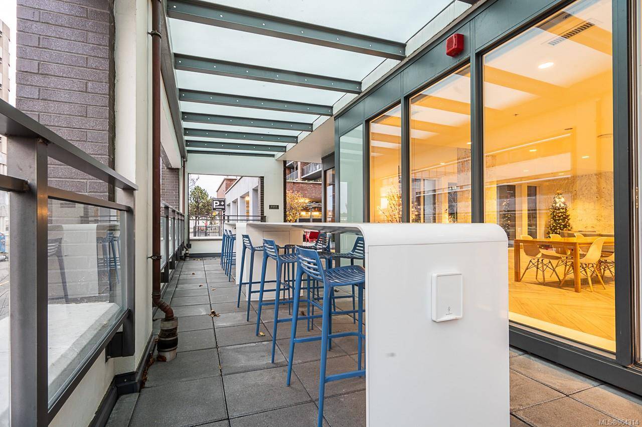 777kit | Apartments Homes Suites for Rent Victoria BC Outdoor patio with blue high stools along a long white counter under a glass roof beside a glass walled cafe interior