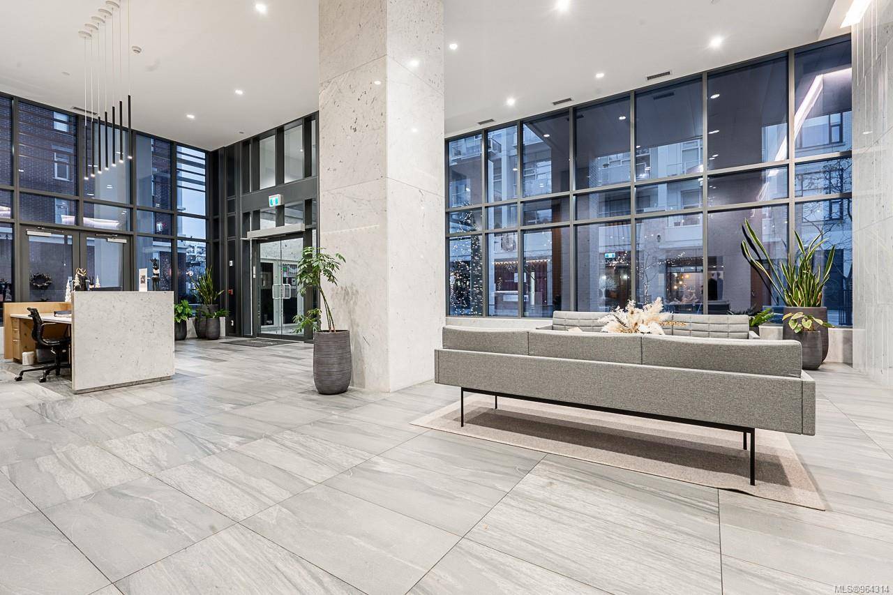 777lobby | Apartments Homes Suites for Rent Victoria BC Modern office lobby with a gray sectional sofa marble columns and large windows showing city lights outside