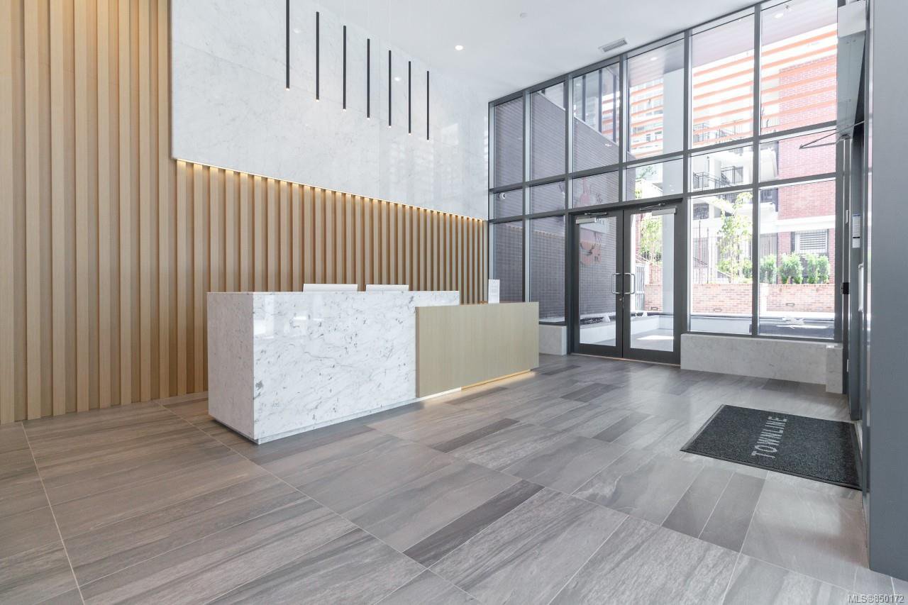 concierge | Apartments Homes Suites for Rent Victoria BC Modern office lobby with a white marble reception desk vertical wood slat wall and expansive glass entry doors letting in daylight
